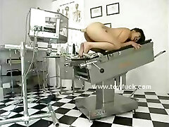 Brunette naked on the doctor table with legs opened up wide is prepped for toy penetrations