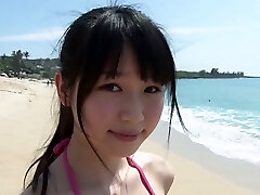 Slim Japanese girl Tsukasa Arai walks on a sandy beach under the sun