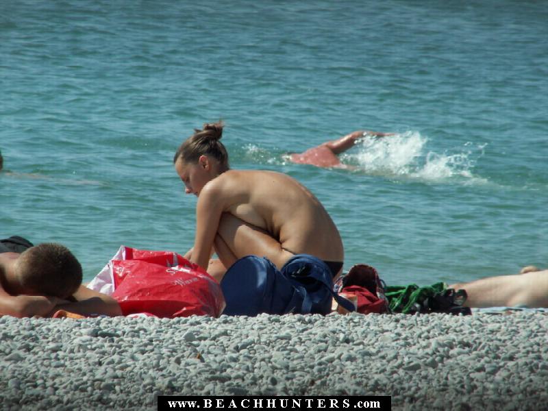 Topless beach chick pulls down her tiny black panties