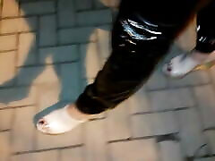 crossdresser on the street in latex leggings and high heels